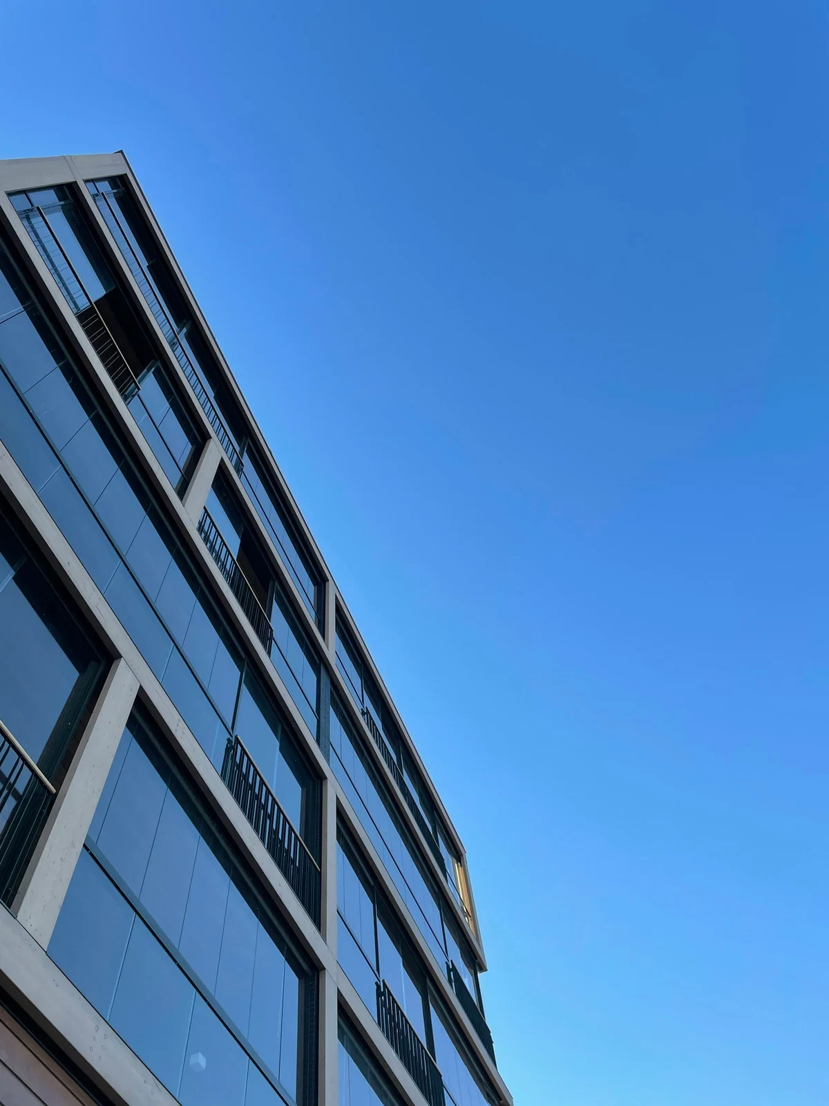 Minimal blue glass facade against a clear sky
